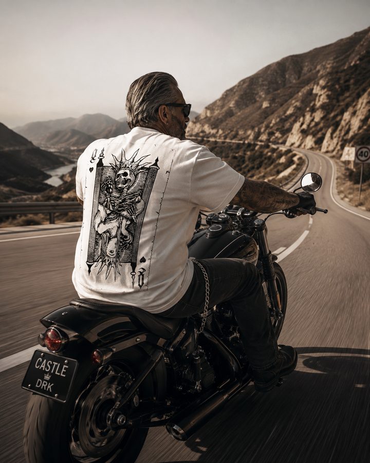 Motociclista con polo Castle blanco en la carretera sobre una Harley